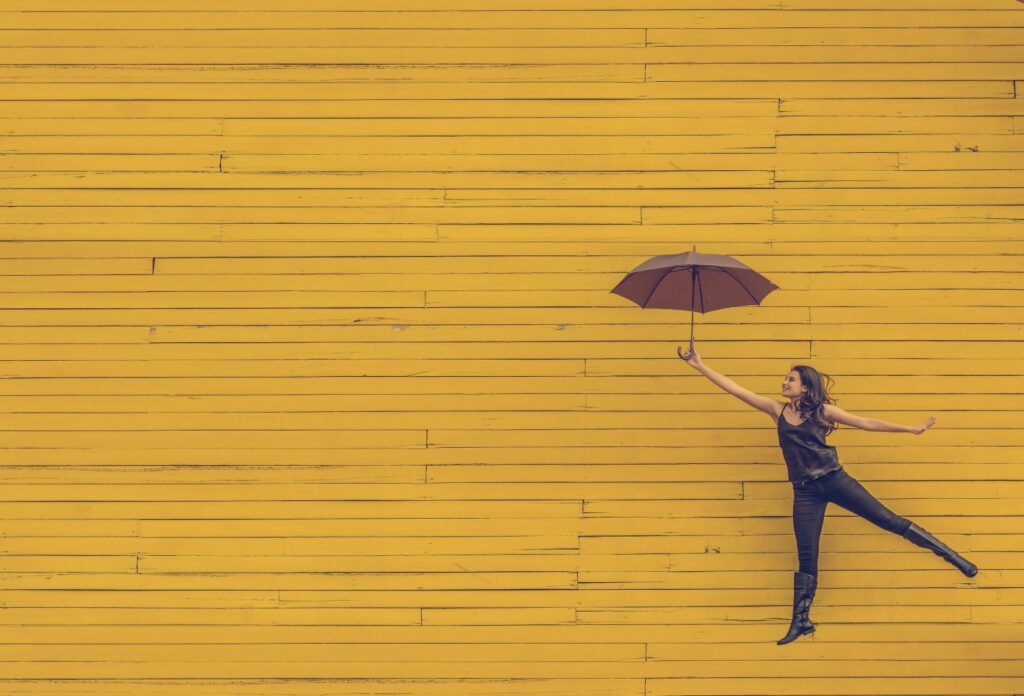 woman holding umbrella in front of yellow brick wall